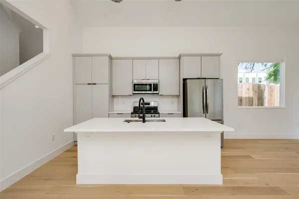 a room with kitchen island a sink a stove and refrigerator