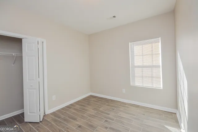 an empty room with wooden floor and windows