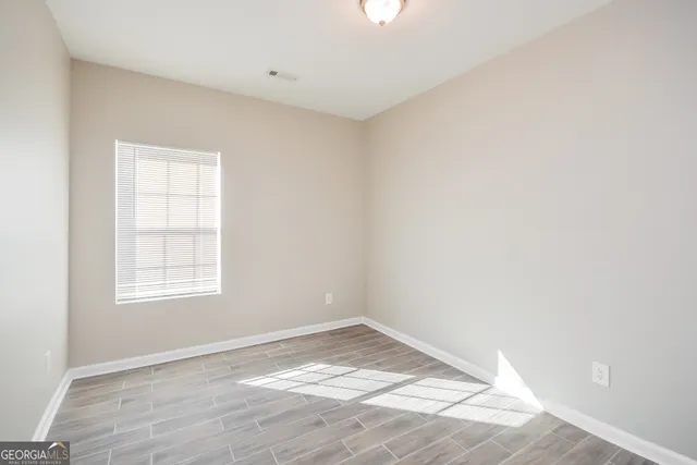 an empty room with wooden floor and windows