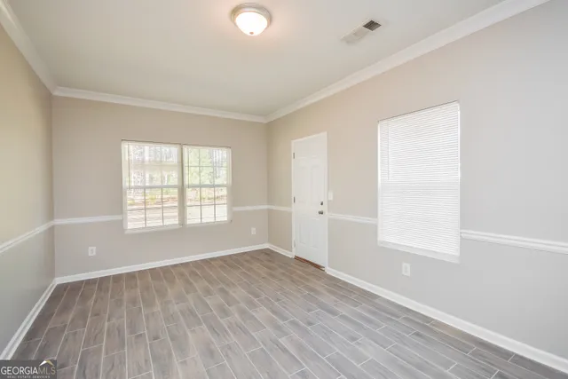 an empty room with wooden floor and windows