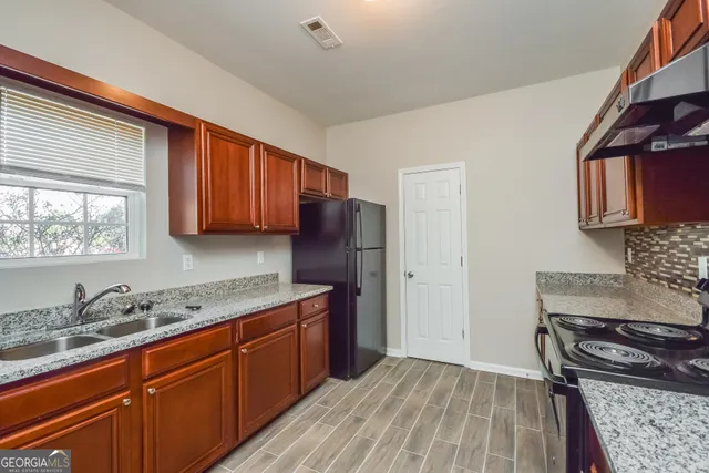 a kitchen with granite countertop wooden cabinets and a stove top oven