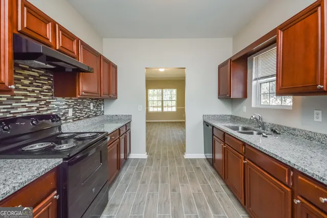 a kitchen with stainless steel appliances granite countertop wooden cabinets stove top oven and sink