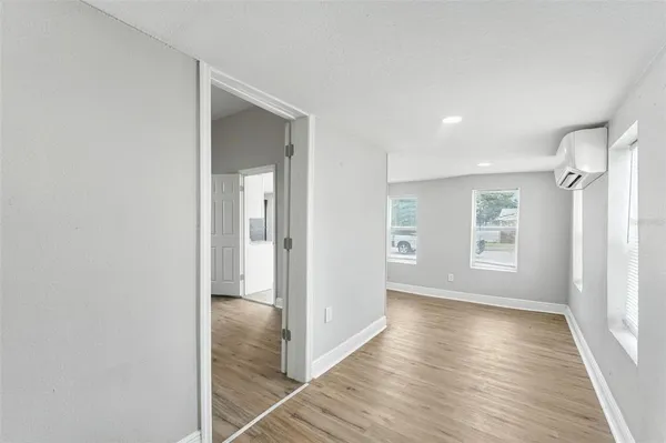 a view of hallway with window and wooden floor