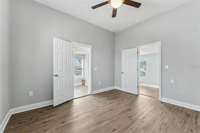 an empty room with wooden floor and ceiling fan