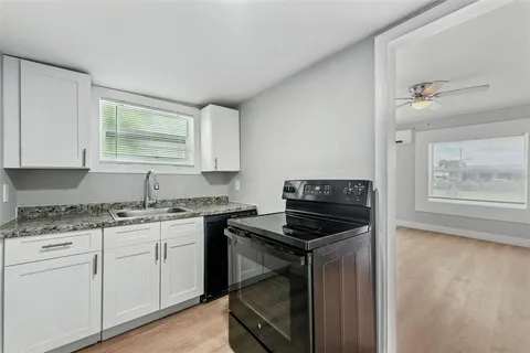 a kitchen with granite countertop a stove sink and cabinets