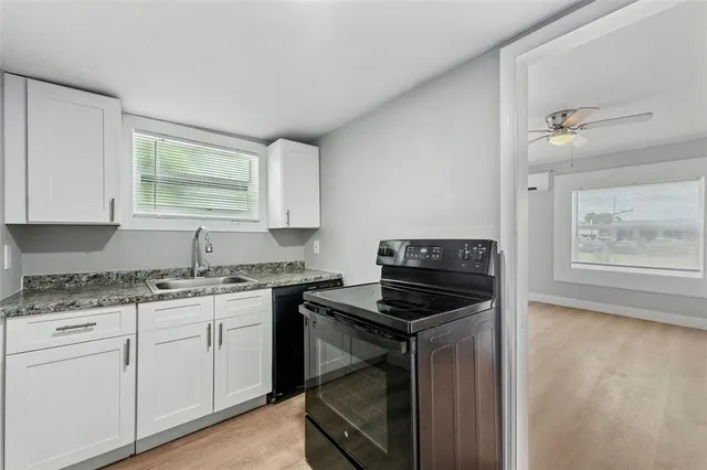 a kitchen with granite countertop a stove sink and cabinets