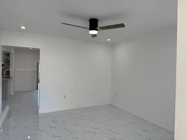 an empty room with a ceiling fan and window