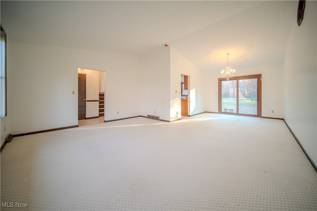 698 Albert Horning Road Atwater, OH 44201 - Photo 19 of 40 Empty room featuring a chandelier, lofted ceiling, and light colored carpet