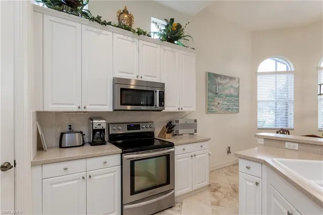 a kitchen with white cabinets and sink
