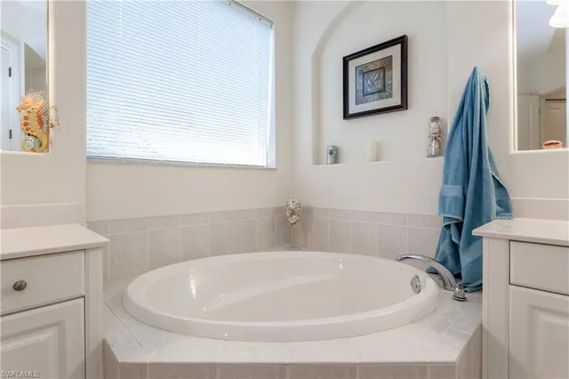 a white bath tub sitting next to a white sink and vanity