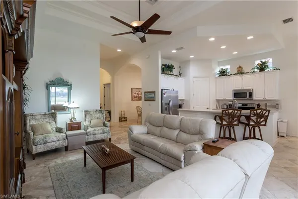 a living room with furniture kitchen view and a chandelier