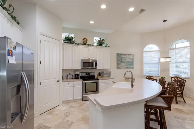 a kitchen with stainless steel appliances a sink a stove a refrigerator a center island and a stove