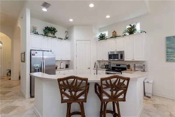 a kitchen with stainless steel appliances granite countertop a refrigerator a stove a sink a dining table and chairs with wooden floor