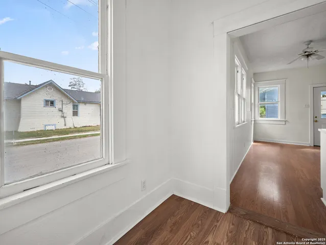 an empty room with wooden floor and windows
