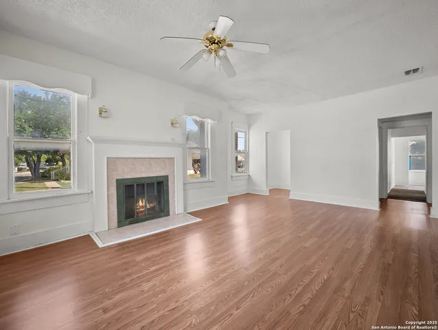 a view of empty room with wooden floor fireplace and a window