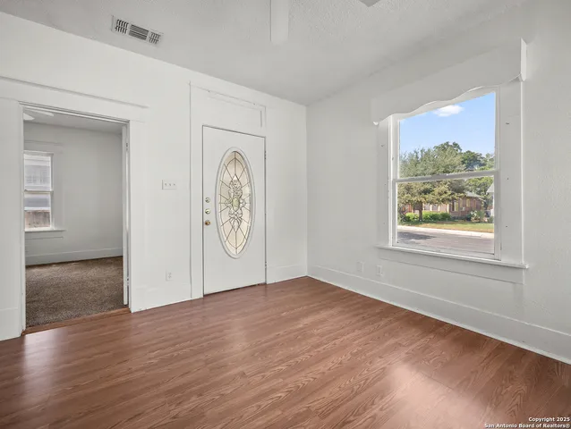 a view of an empty room with window and wooden floor