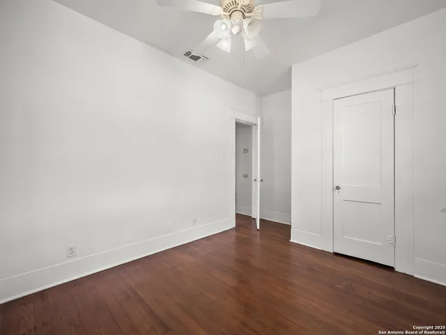 an empty room with wooden floor and fan