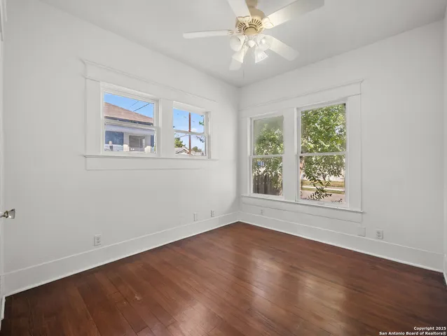 a view of an empty room with wooden floor and a window