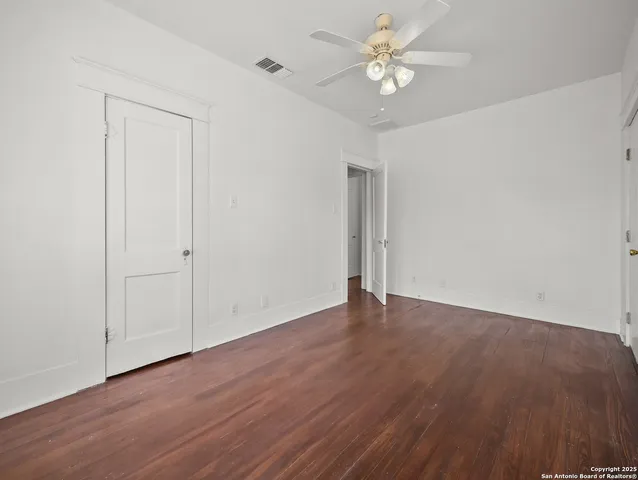 an empty room with wooden floor and ceiling fan