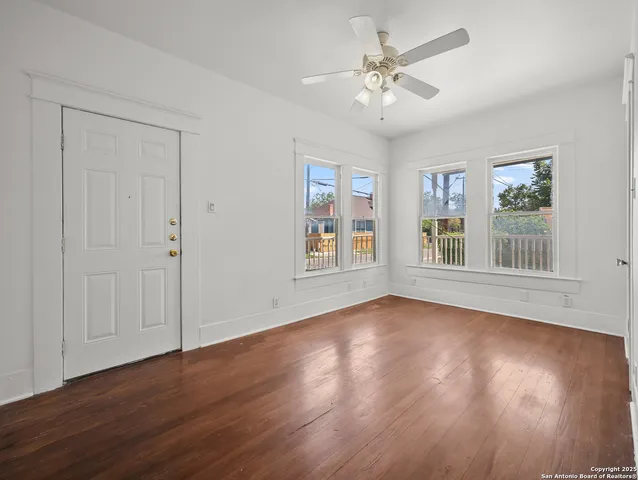 a view of an empty room with window and wooden floor