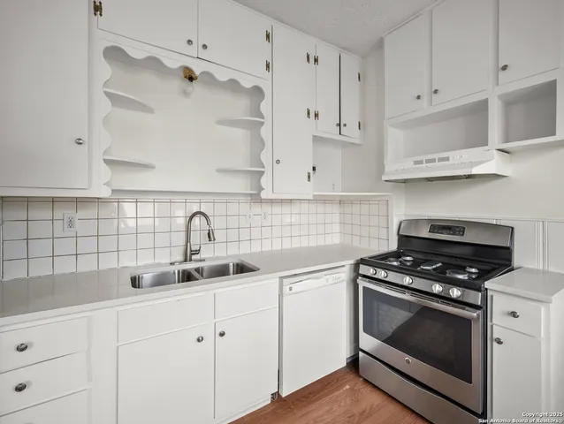 a kitchen with white cabinets and appliances