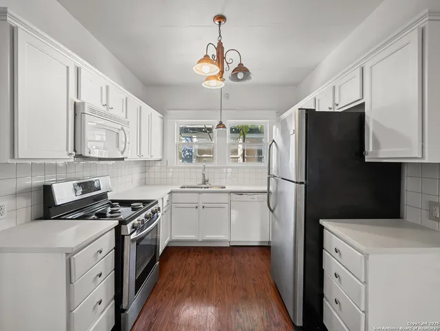 a kitchen with a refrigerator stove and white cabinets