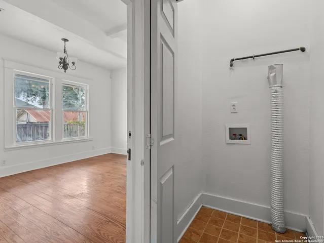 a view of an empty room with window and wooden floor