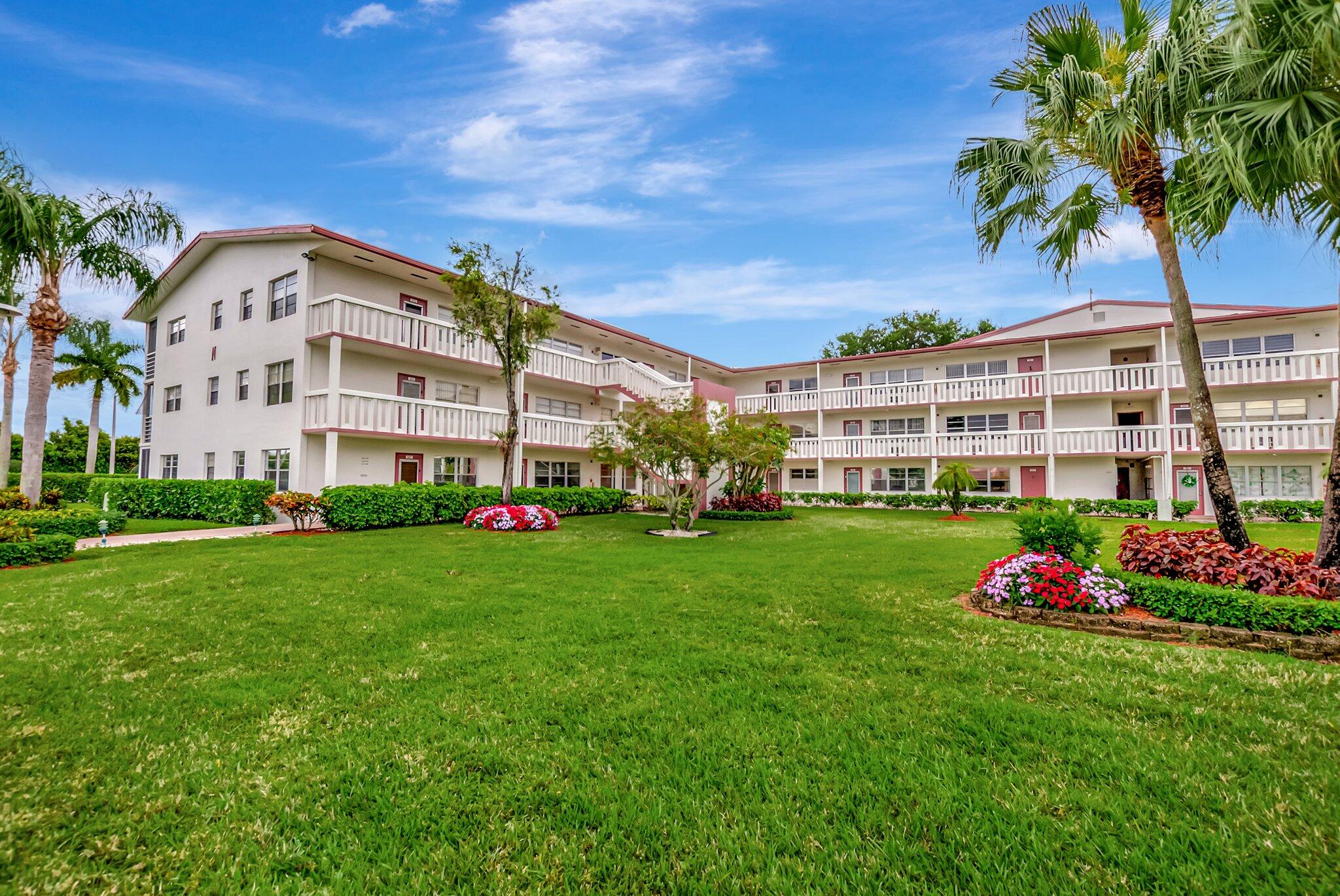 a front view of a multi story residential apartment building with yard and green space