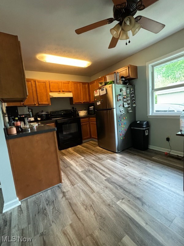 1534 Hubbard Road Madison, OH 44057 - Photo 6 of 15 Kitchen with black range with electric cooktop, under cabinet range hood, freestanding refrigerator, dark countertops, and light wood-style floors