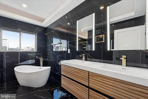 a bathroom with a double vanity sink mirror and bathtub