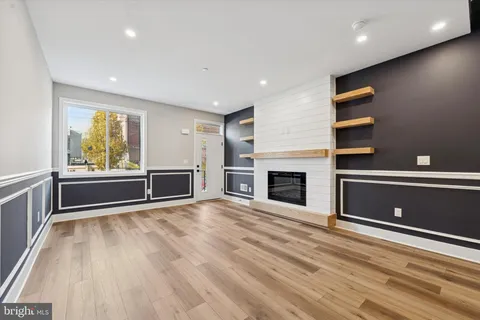 an empty room with wooden floor fireplace and windows