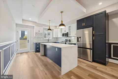 a kitchen with stainless steel appliances granite countertop a refrigerator a sink dishwasher a kitchen island with wooden floor and cabinets