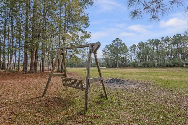 a view of a blue house with a yard and sitting area
