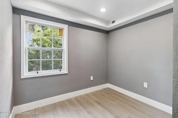 an empty room with wooden floor and windows