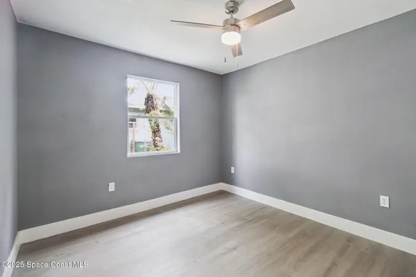 an empty room with a window and ceiling fan