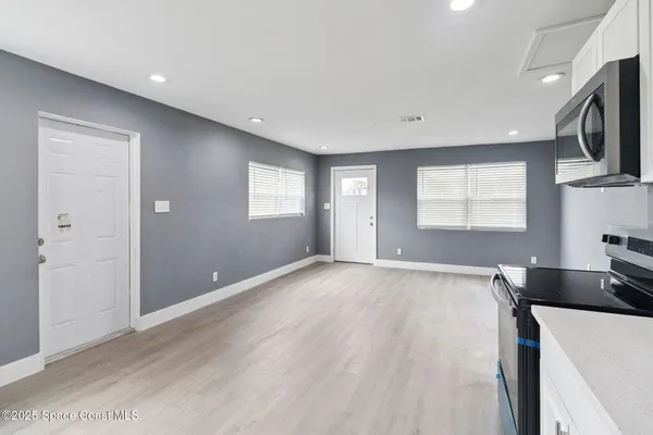 a view of an empty room with a window and wooden floor