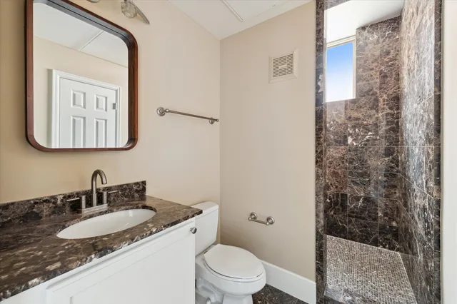 a bathroom with a granite countertop sink toilet and shower