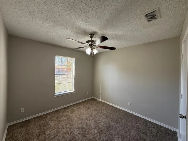 an empty room with windows and fan