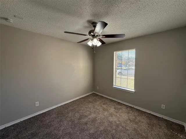 an empty room with windows and chandelier fan