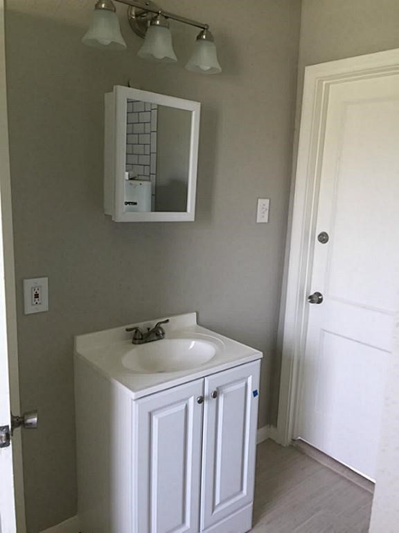 3502 Rosedale Street Houston, TX 77004 - Photo 15 of 17 Bathroom features a sleek white vanity with ample storage, complemented by a modern mirror cabinet and elegant light fixture.