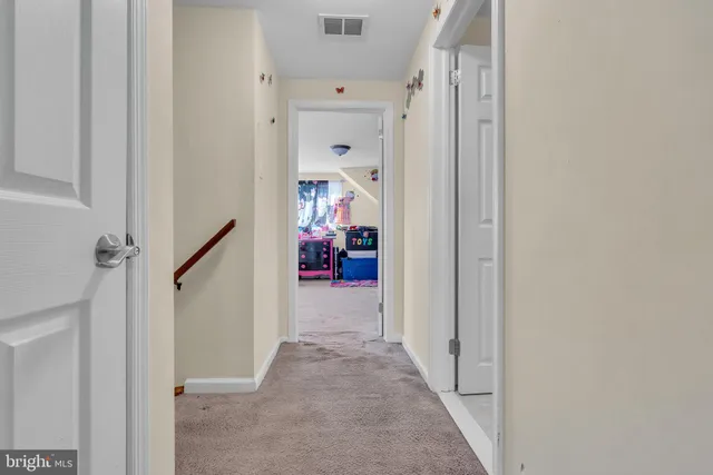 a view of a hallway with white walls and stairs