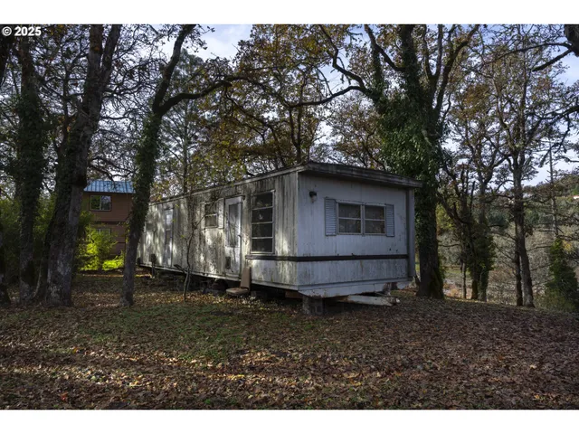 a view of a barn in the backyard with large trees