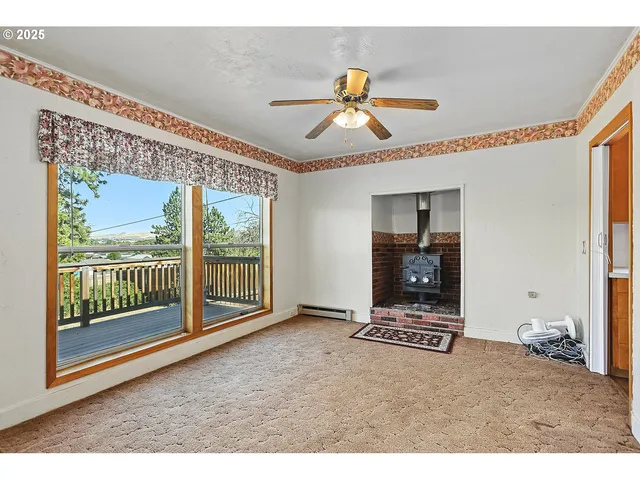 a view of an empty room with window and wooden floor