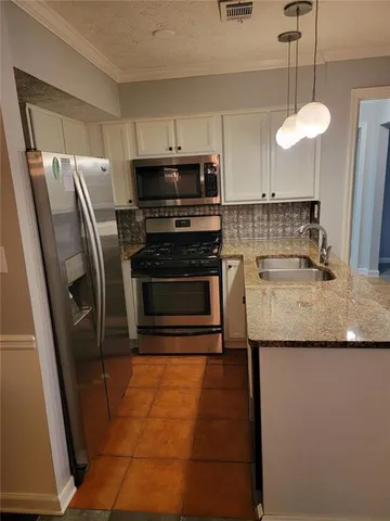 a kitchen with stainless steel appliances granite countertop a sink a stove a microwave a refrigerator a sink and dishwasher