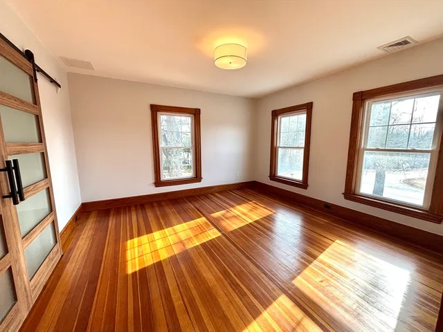 an empty room with wooden floor and windows