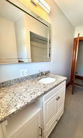 a bathroom with a granite countertop sink and a mirror
