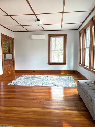 a view of a bedroom with wooden floor and window