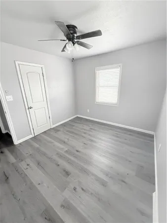 an empty room with wooden floor fan and windows