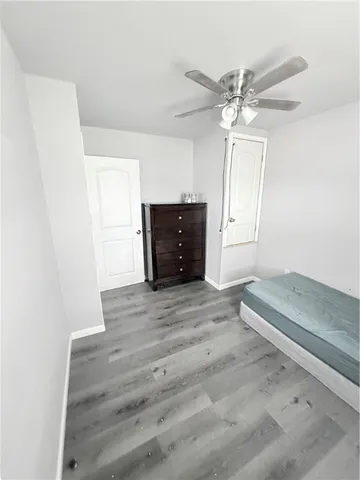 an empty room with wooden floor ceiling fan and window