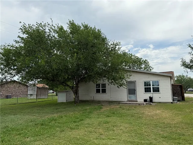 a backyard of a house with plants and large tree